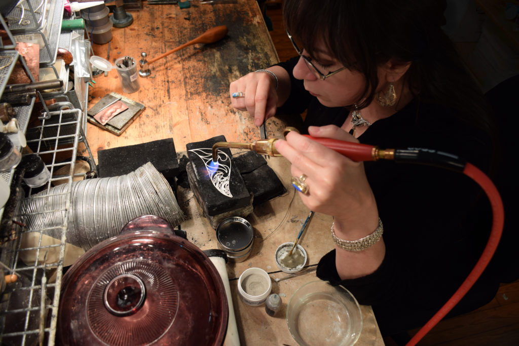 Victoria soldering filler wires into the filigree frame prior to bending the 3D structure