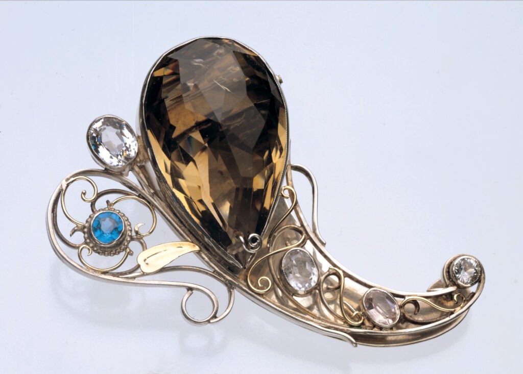 Arts & Crafts Clip Brooch Below by George Edward Hunt Fabricated, filigree, circa 1930 Silver, gold, smoky quartz, crystals, spinel 2.76 x 1.79 in Collection of The Richard H. Driehaus Museum, Chicago Image courtesy of Tadema Gallery, London
